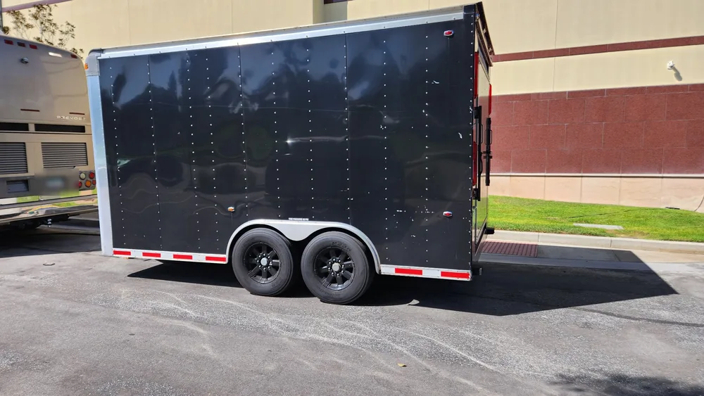 A black 15 foot enclosed cargo trailer broken down in a parking lot in Riverside