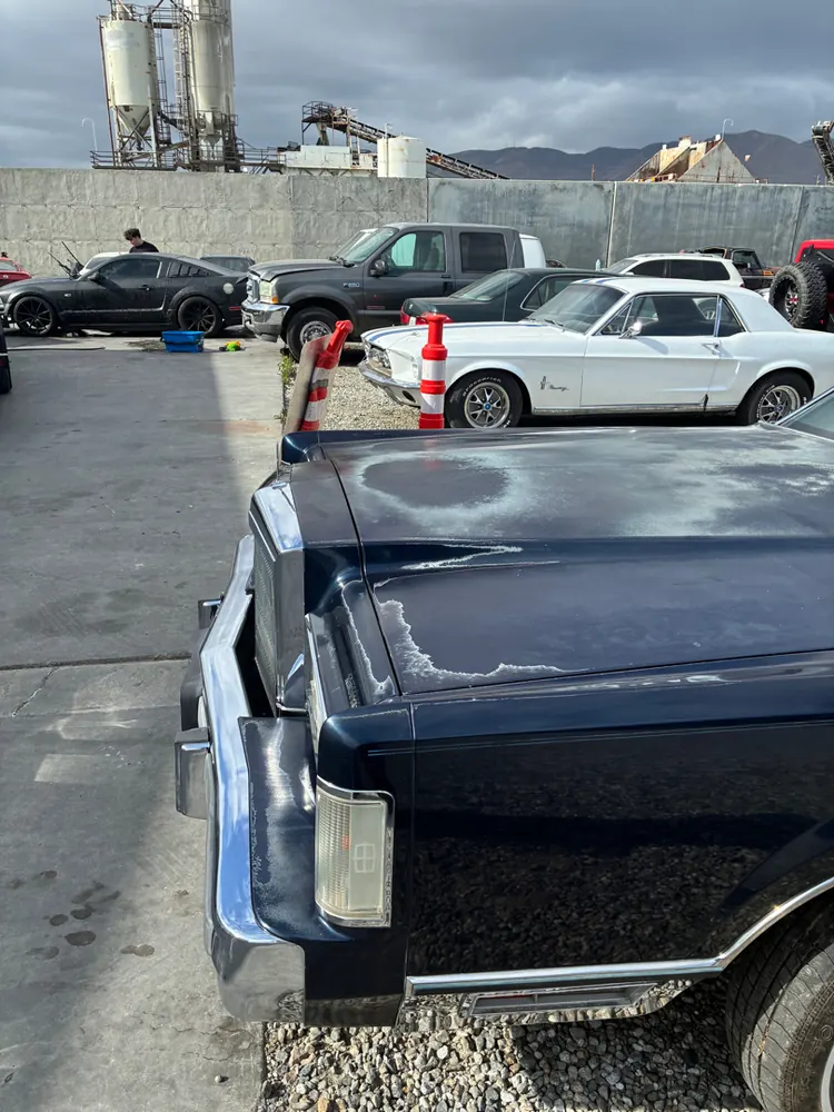 Lincoln Town Car rear quarter at the shop, classic Mustang in the background