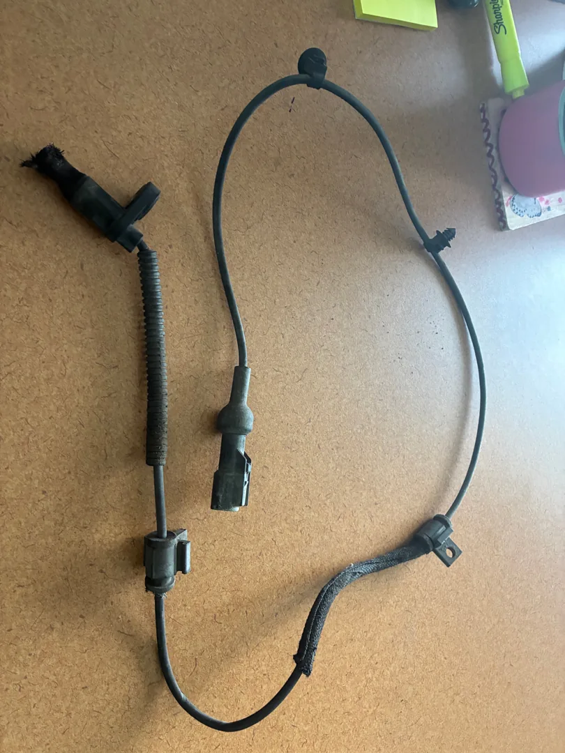 Replacement ABS wheel speed sensor and wiring harness laid out before fitting