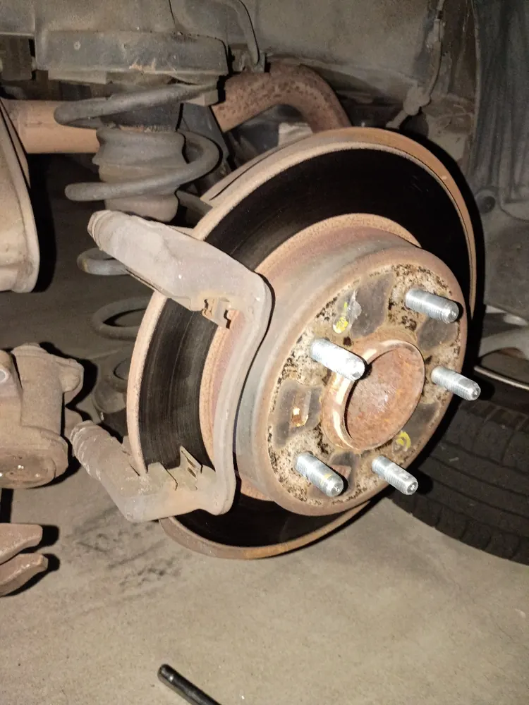 Worn rear brake rotor and hub before replacement during a mobile brake job