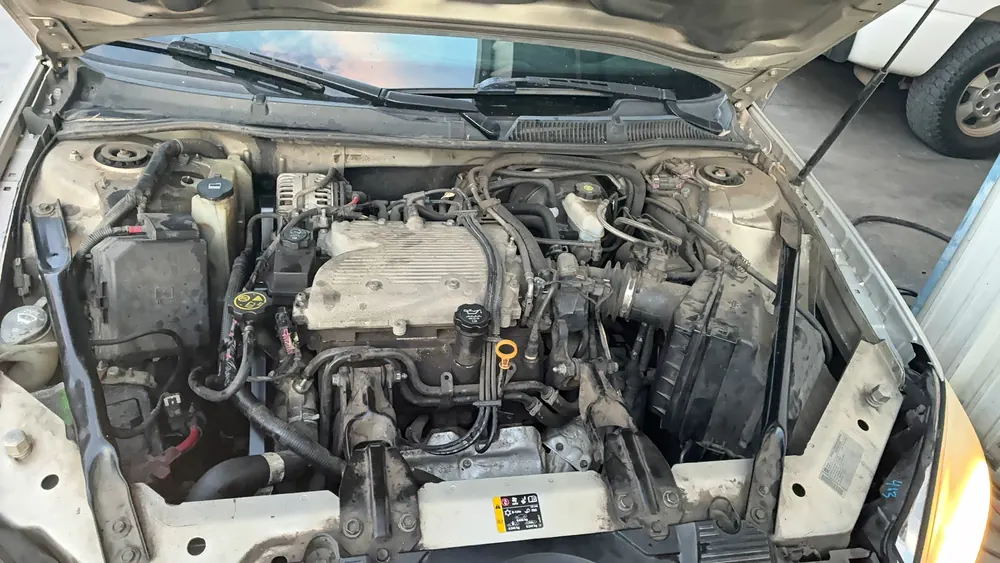 Chevy Impala engine bay with the radiator removed during cooling system service