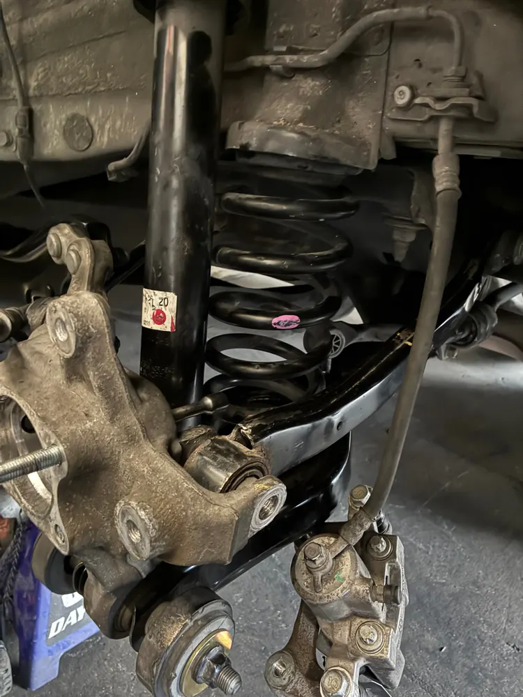 Rear suspension knuckle, spring, and brake assembly during suspension repair on a Kia Optima